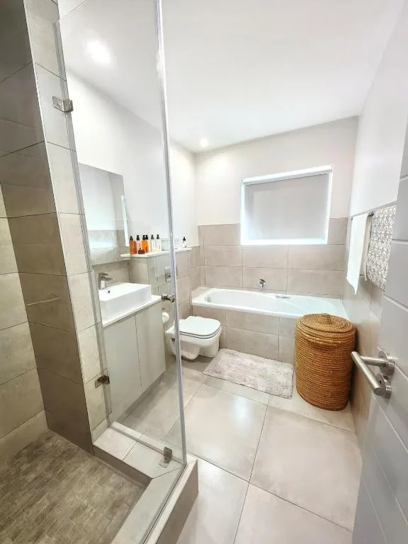 Modern bathroom with walk-in shower, vanity, toilet, and bathtub