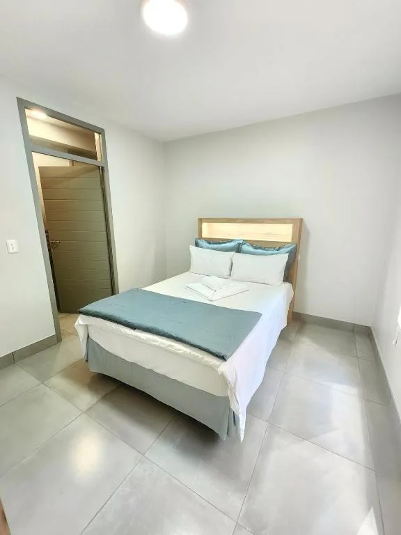 Clean bedroom with queen bed, wooden headboard, and teal throw blanket