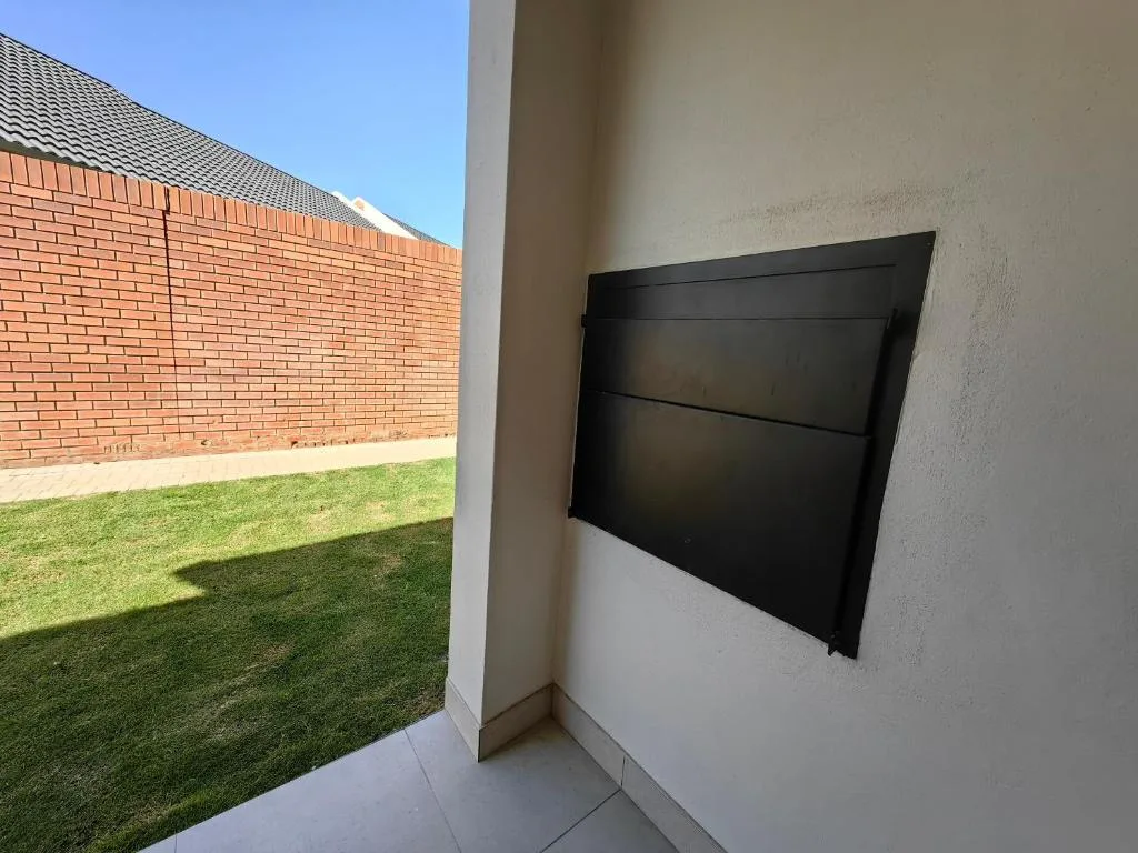 Outdoor patio space with mounted black television and brick wall view