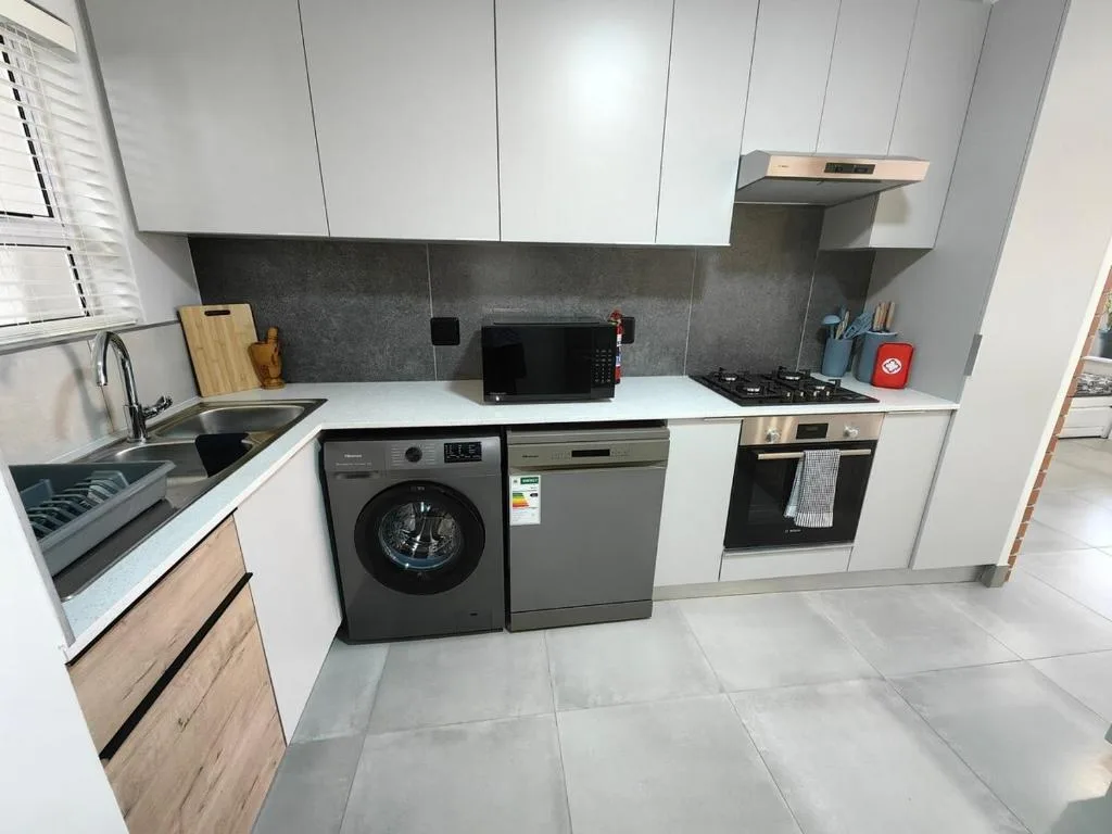 Modern kitchen with white cabinetry, dark backsplash, gas cooktop, and integrated appliances