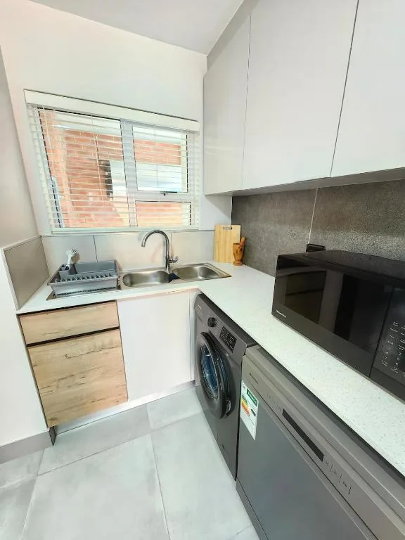 Modern kitchen with white cabinetry, stainless steel appliances, and window view
