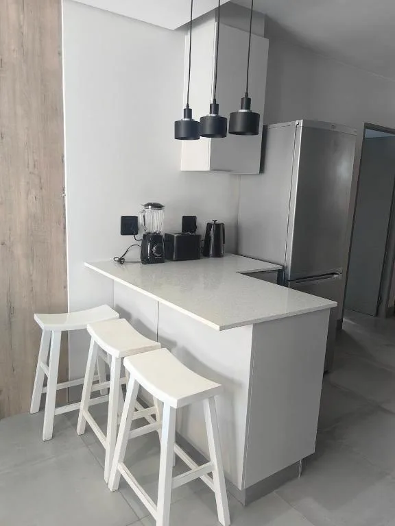 Modern kitchen with white counter, bar seating, and pendant lighting