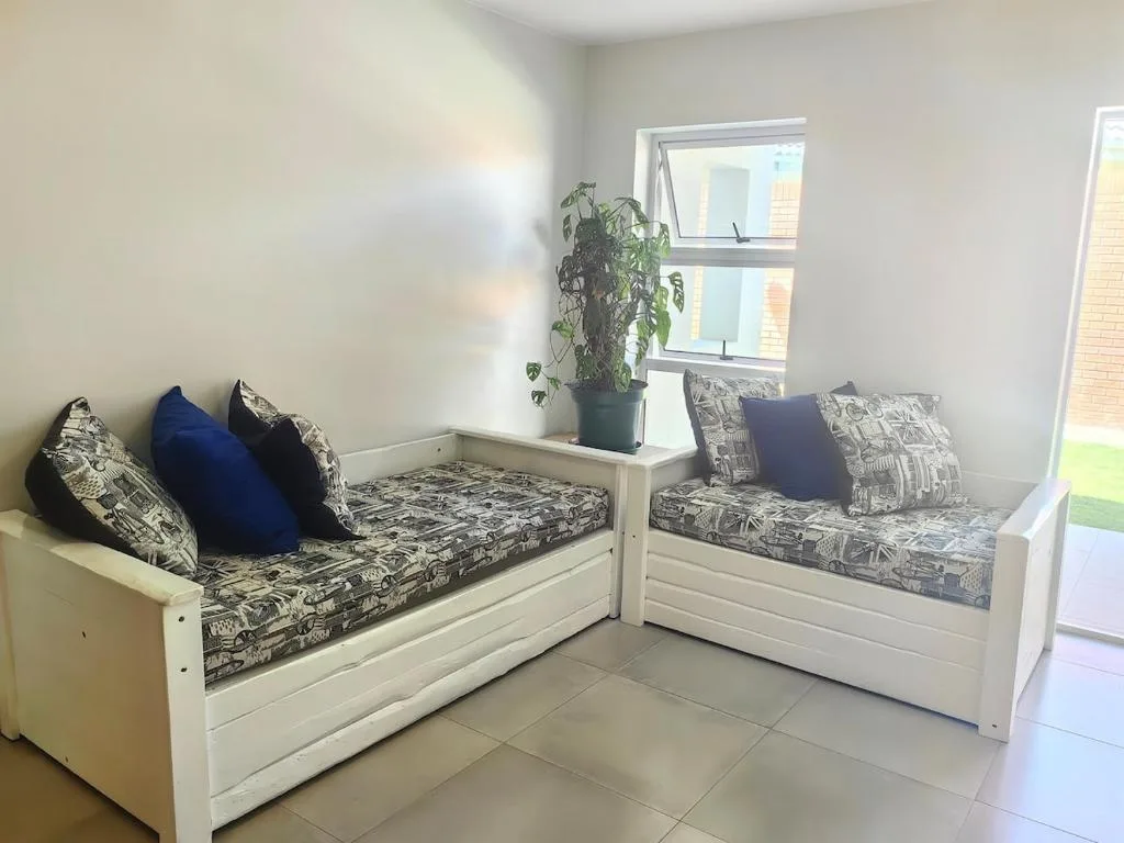 Light-filled lounge with two white built-in seating benches and decorative pillows