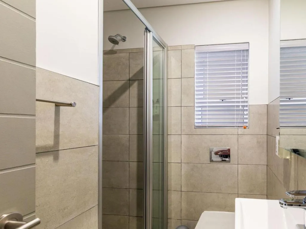 Modern bathroom with tiled shower enclosure and natural light from window