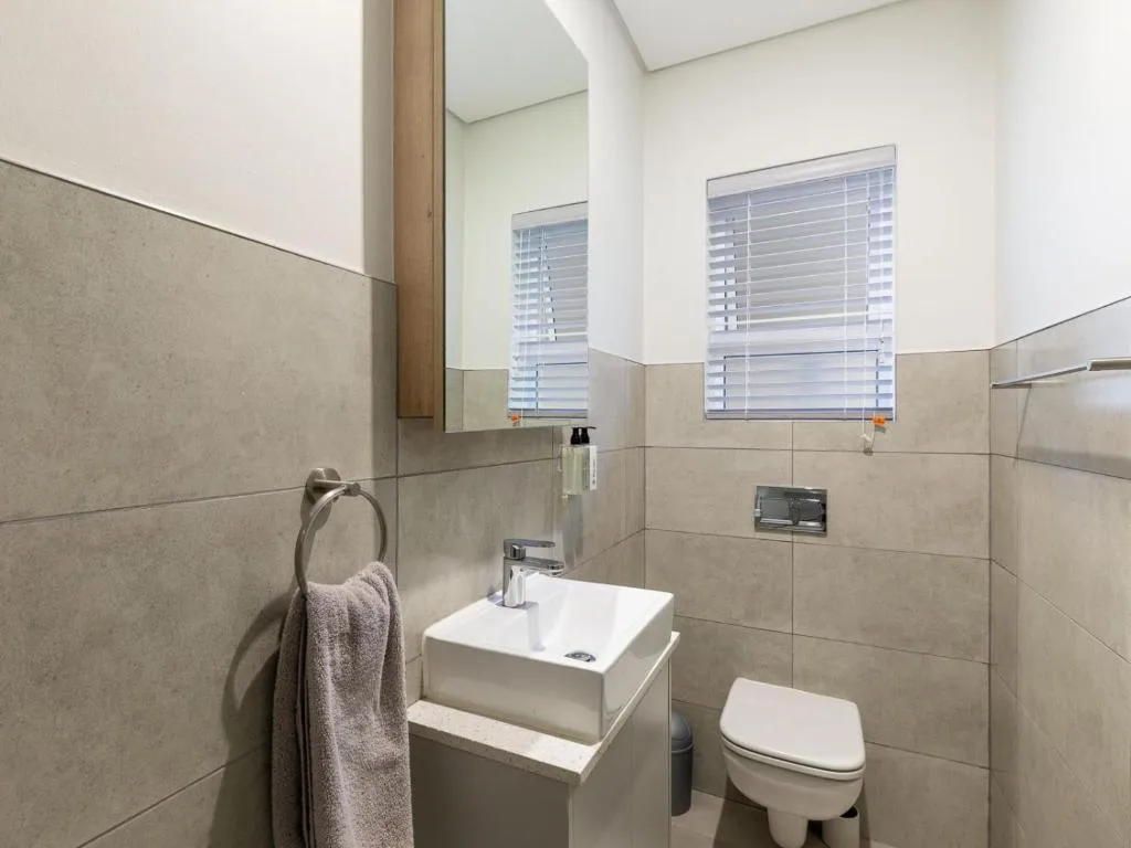 Modern bathroom with sink vanity, toilet, and tiled walls