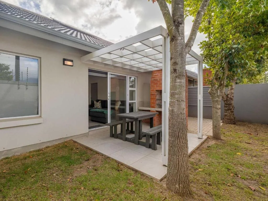 Modern patio with pergola, dining table, and mature tree shade