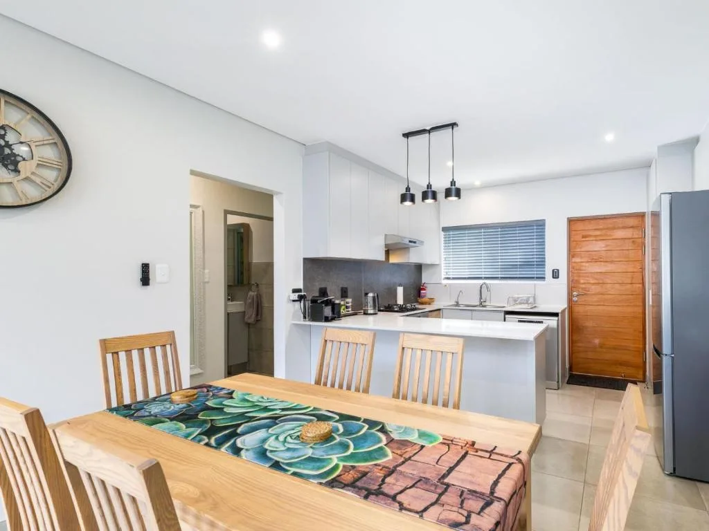 Open-plan dining and kitchen with wooden table and modern pendant lights