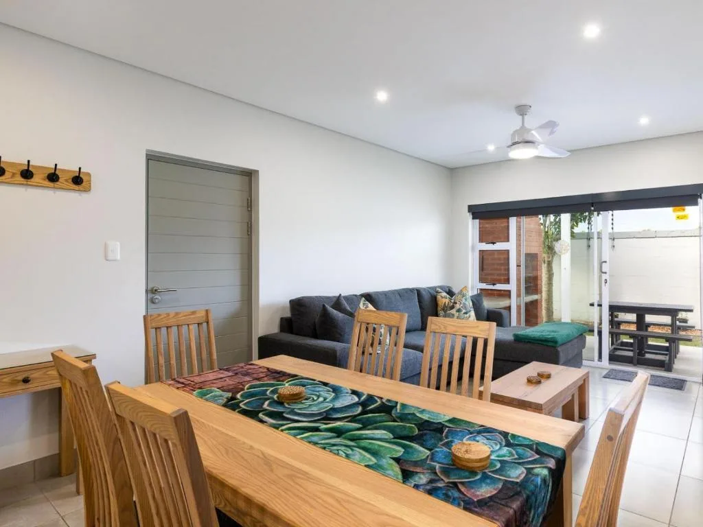 Open-plan dining and lounge area with wooden table and black sofa