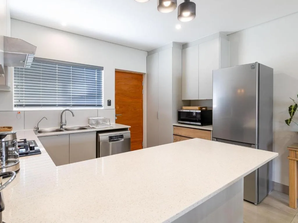 Modern kitchen with white countertop island, stainless steel appliances, and pendant lighting