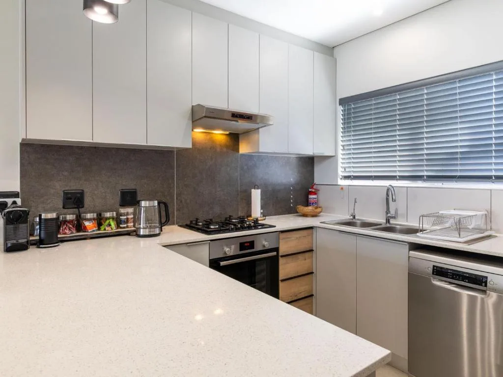 Modern kitchen with white cabinetry, stainless steel appliances, and granite countertops
