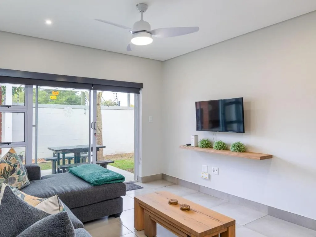 Modern living room with gray sofa, wall-mounted TV, and sliding glass doors to patio