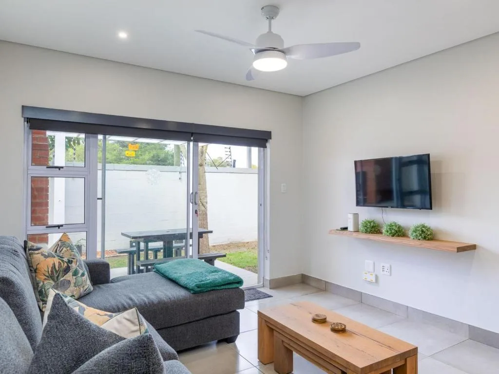 Modern lounge with gray seating, TV, and sliding doors to garden
