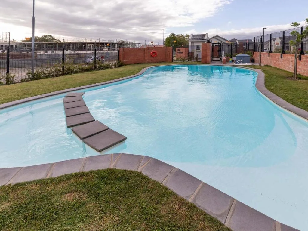 Large curved swimming pool with lounging platforms and surrounding lawn