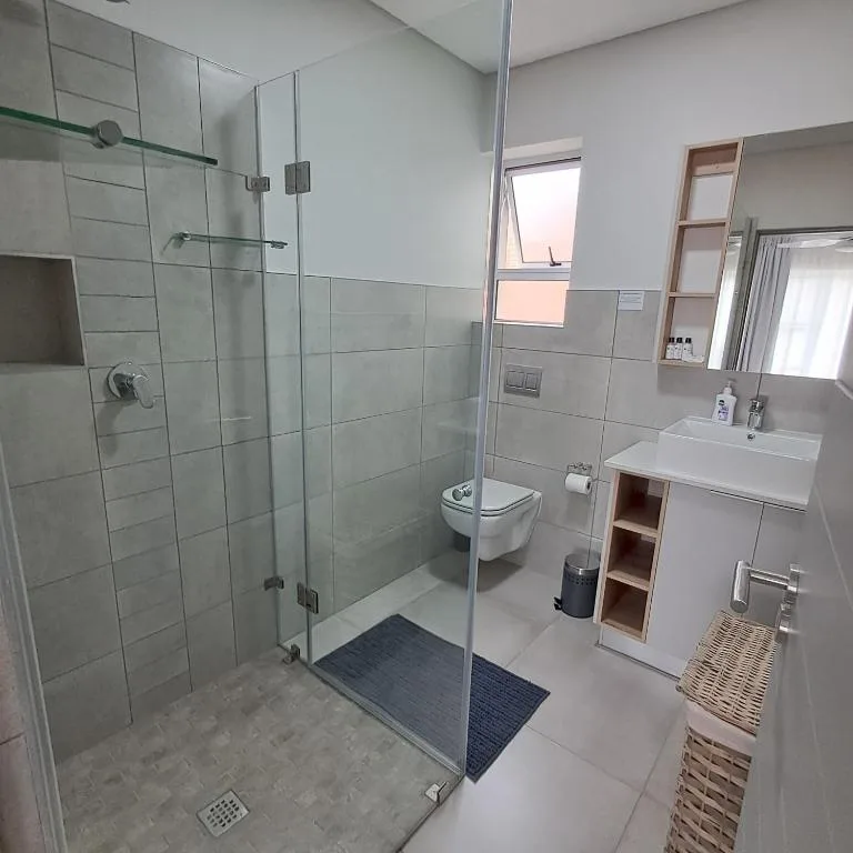 Modern bathroom with glass shower enclosure, wall-mounted toilet, and white vanity sink