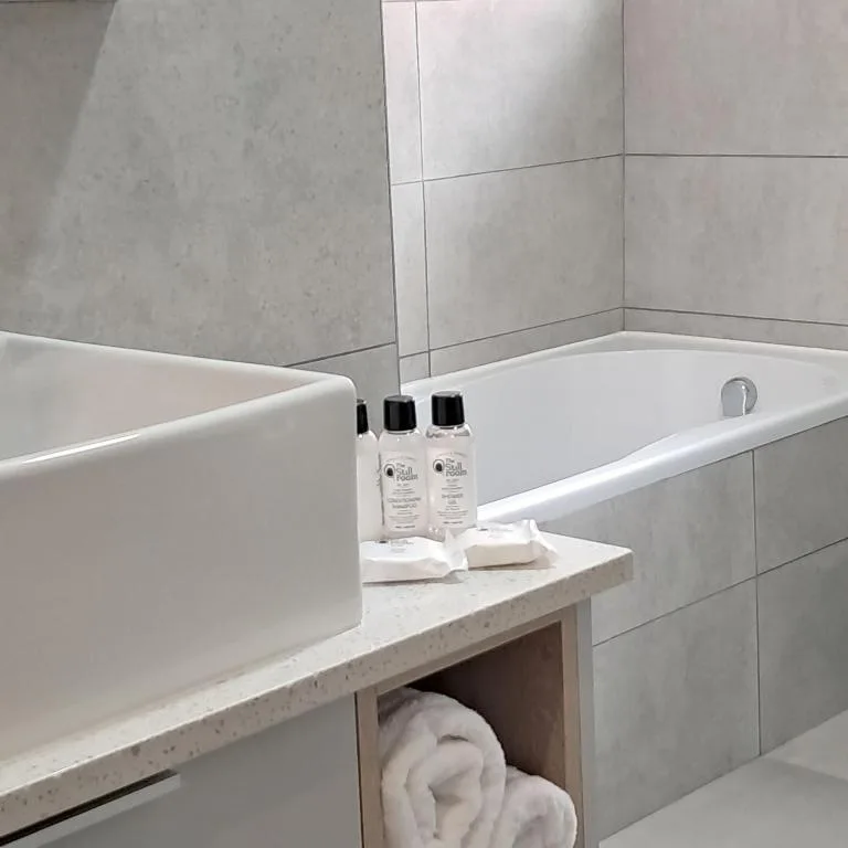 Modern bathroom with white bathtub, sink, and complimentary toiletries displayed