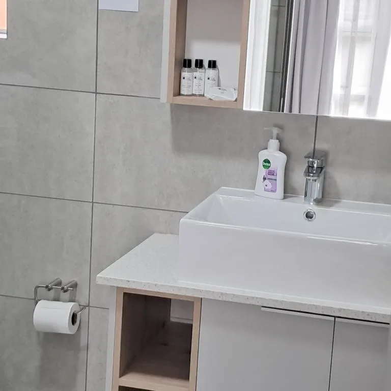 Modern bathroom vanity with white sink, toiletries, and tiled walls