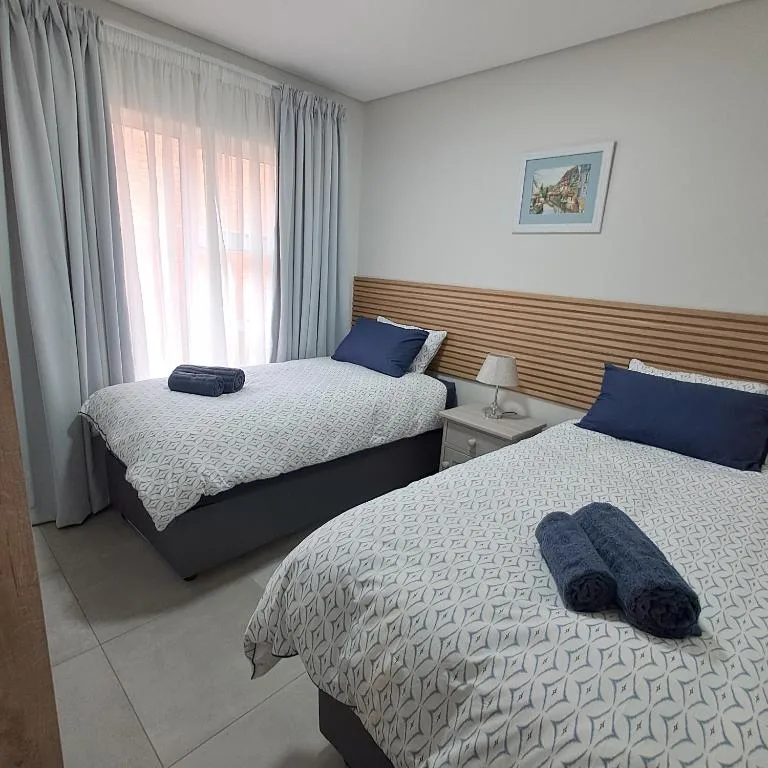 Twin bedroom with wooden headboards, crisp white bedding, navy pillows
