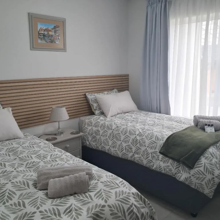Twin beds with leaf-patterned bedding and wooden headboard in bright room
