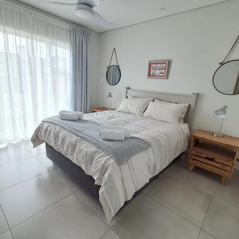 Modern bedroom with striped bedding, wooden nightstand, and sheer curtains