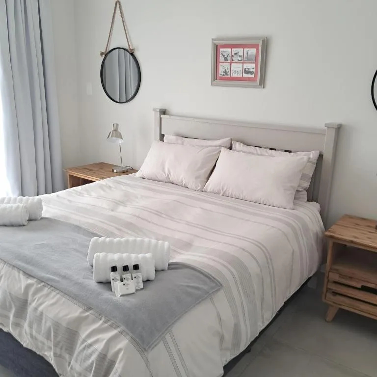 Bright bedroom with queen bed, striped bedding, wooden nightstands, and round mirror