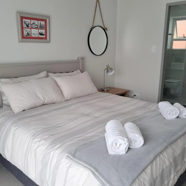 Modern bedroom with neatly made bed and rolled white towels displayed