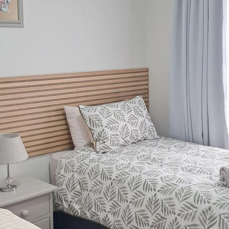Bedroom with wooden headboard and patterned leaf bedding