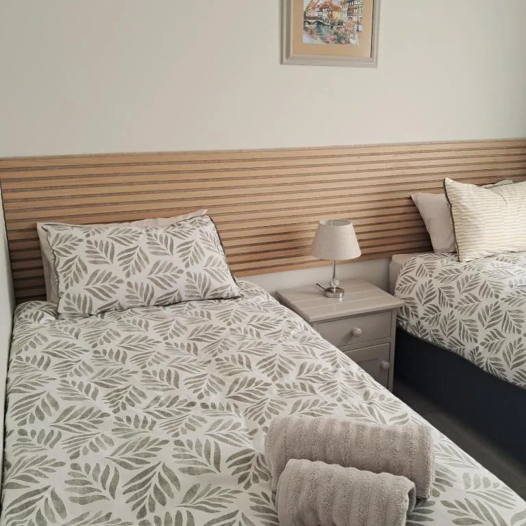 Twin bedroom with leaf-patterned bedding and wooden headboard paneling