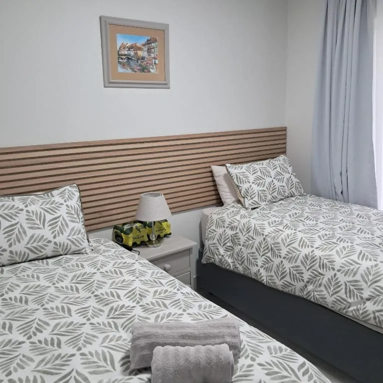 Twin beds with leaf-patterned bedding and modern striped headboard