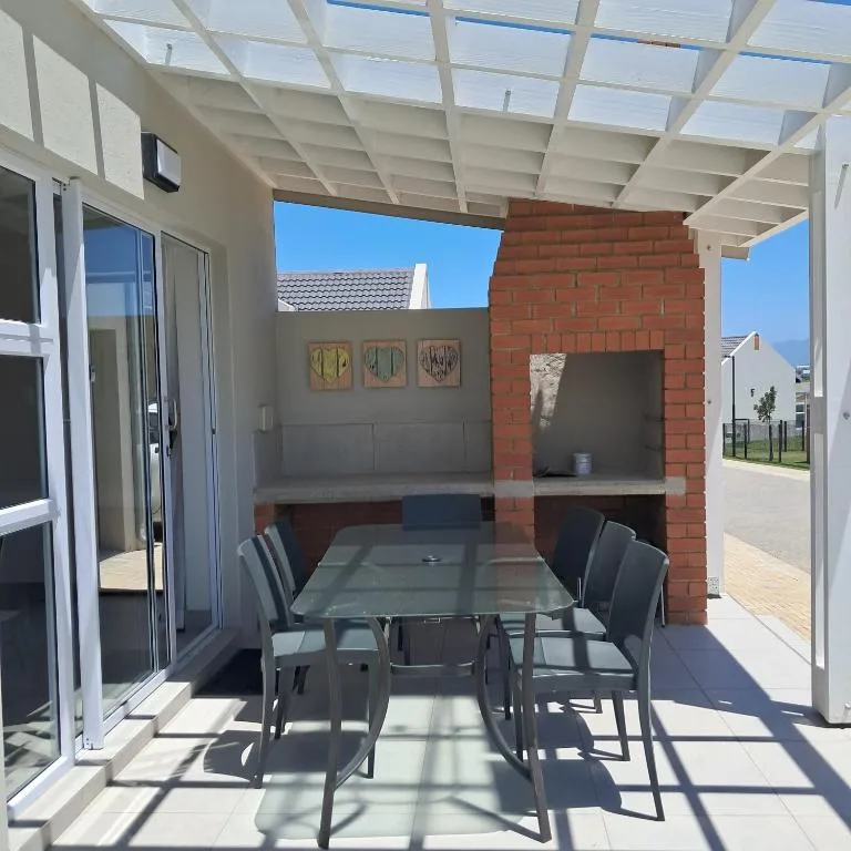 Covered outdoor patio with dining table and brick fireplace feature