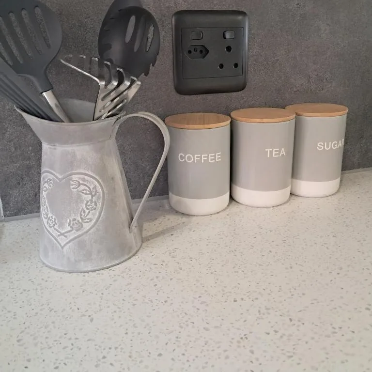 Kitchen counter with utensil holder, storage canisters, and wall socket