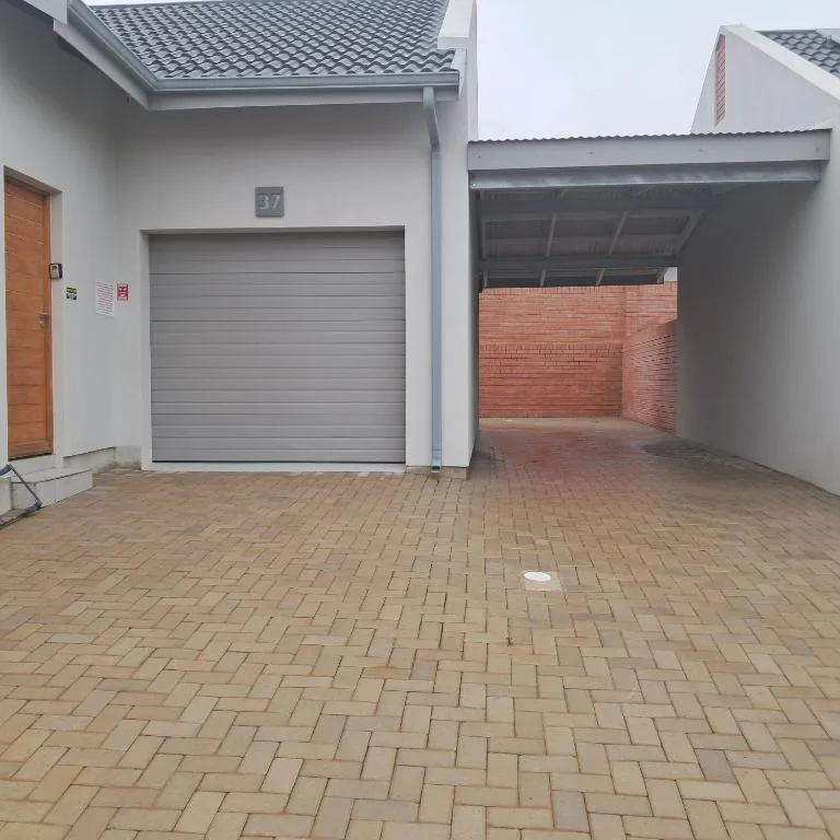 Modern white house with gray garage door and brick carport