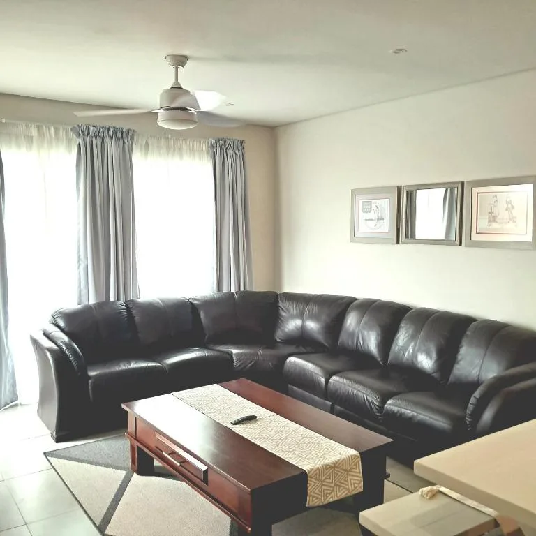 Spacious living room with black leather sectional sofa and wood coffee table
