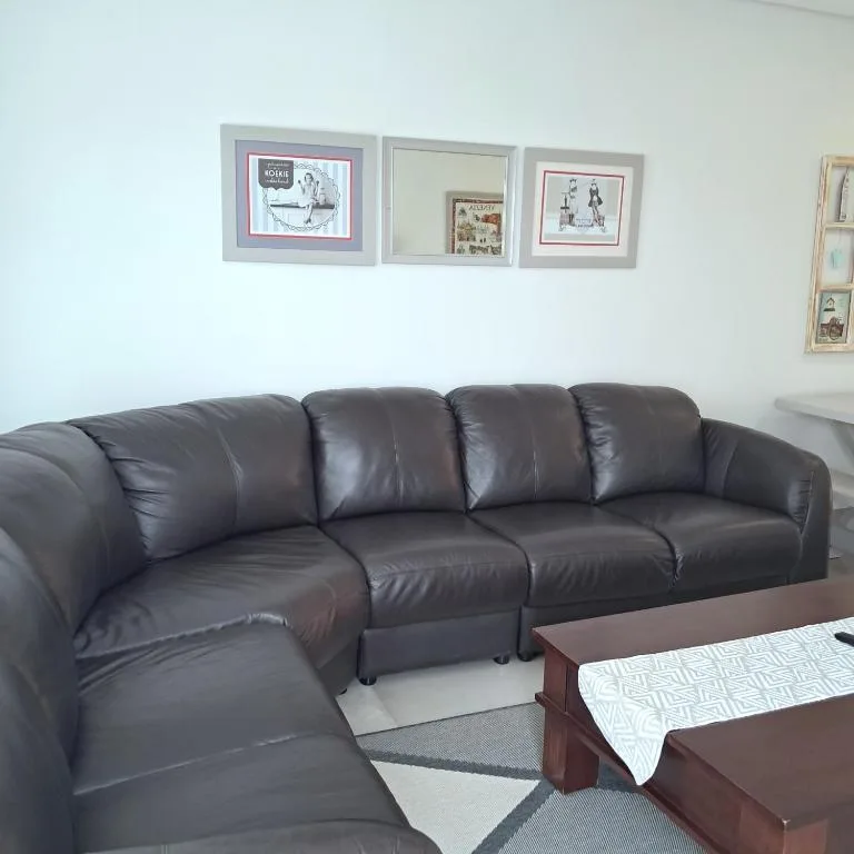 Dark leather sectional sofa with framed artwork displayed on white wall above