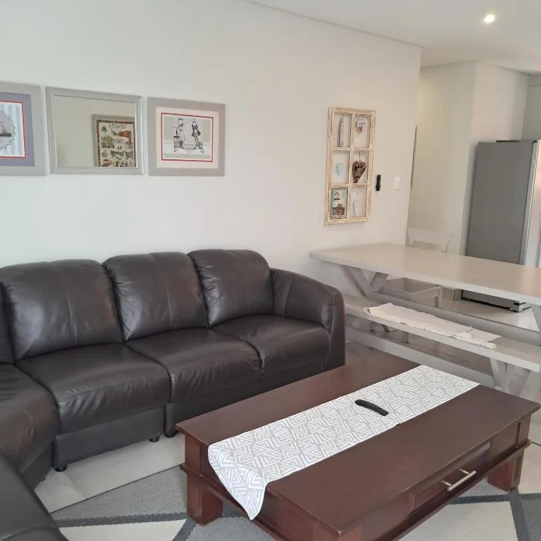 Modern lounge with dark leather sofa, wooden coffee table, and wall art