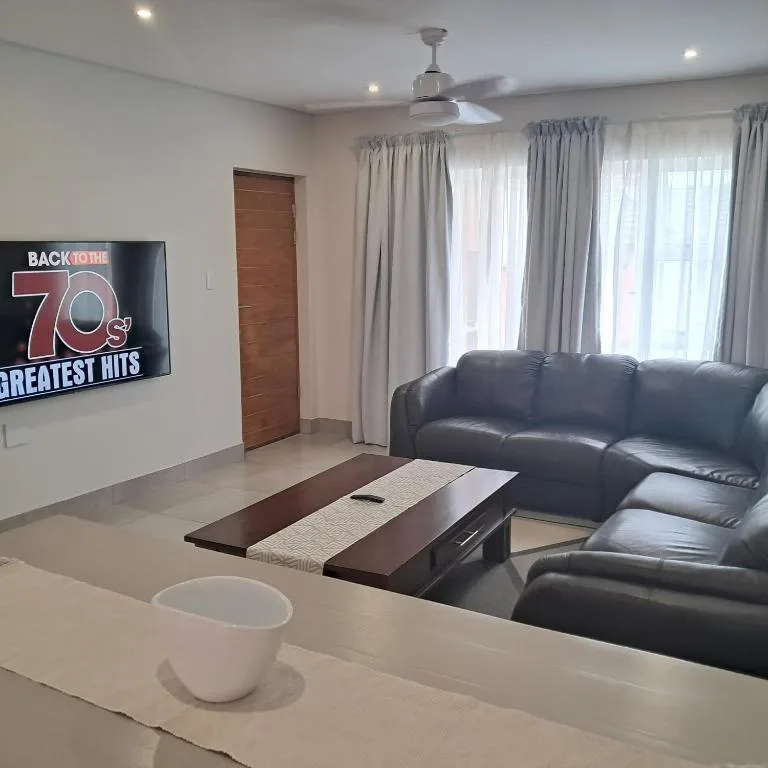 Modern living room with black leather sofa and wall-mounted TV