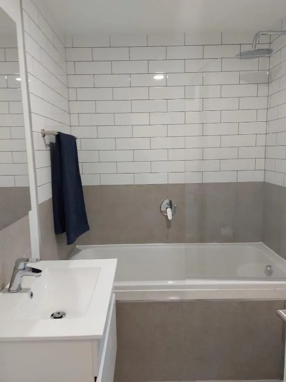 Clean bathroom with white subway tiles, vanity sink, and bathtub with shower