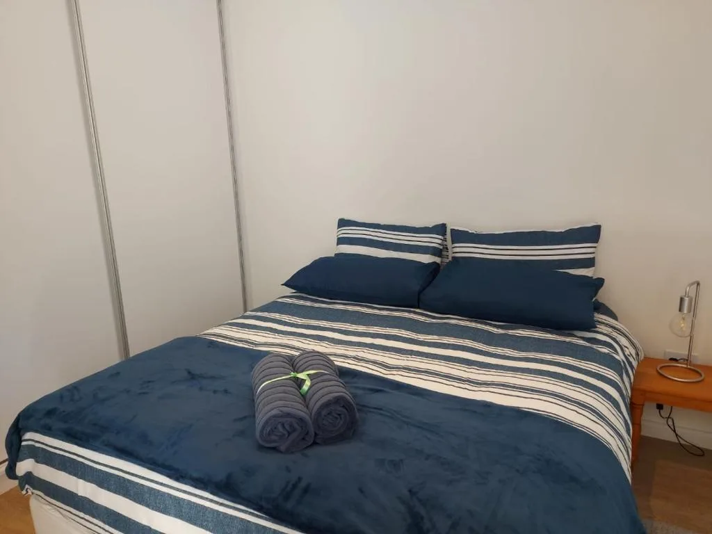 Neatly made bed with navy striped bedding and rolled towels displayed