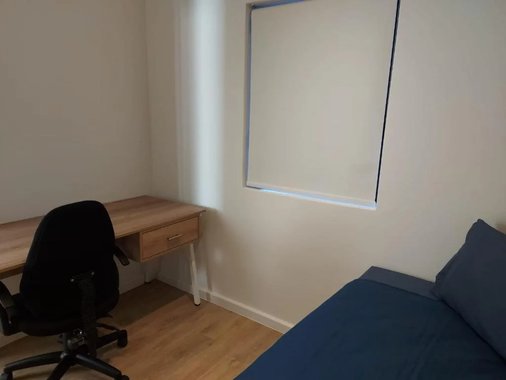 Bedroom with desk, office chair, bed, and wall mirror