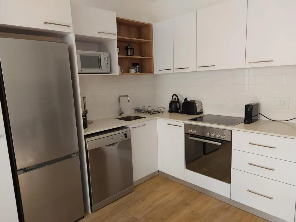 Modern kitchen with white cabinetry, stainless steel appliances, and wooden flooring