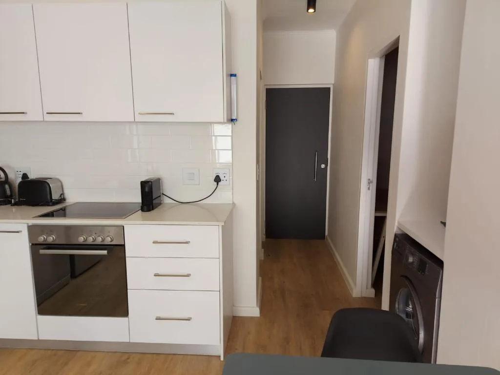 Modern kitchen with white cabinetry, stainless steel oven, and wooden flooring