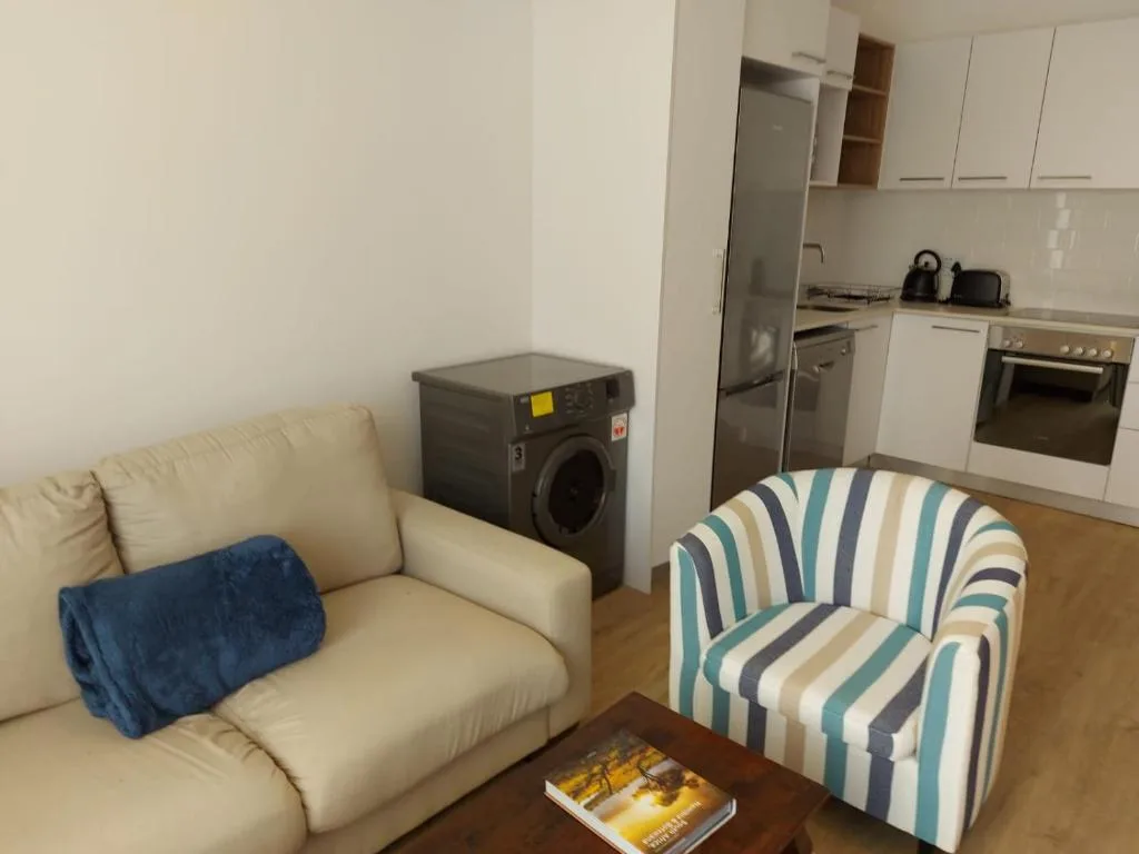 Open-plan lounge and kitchen with cream sofa and striped armchair