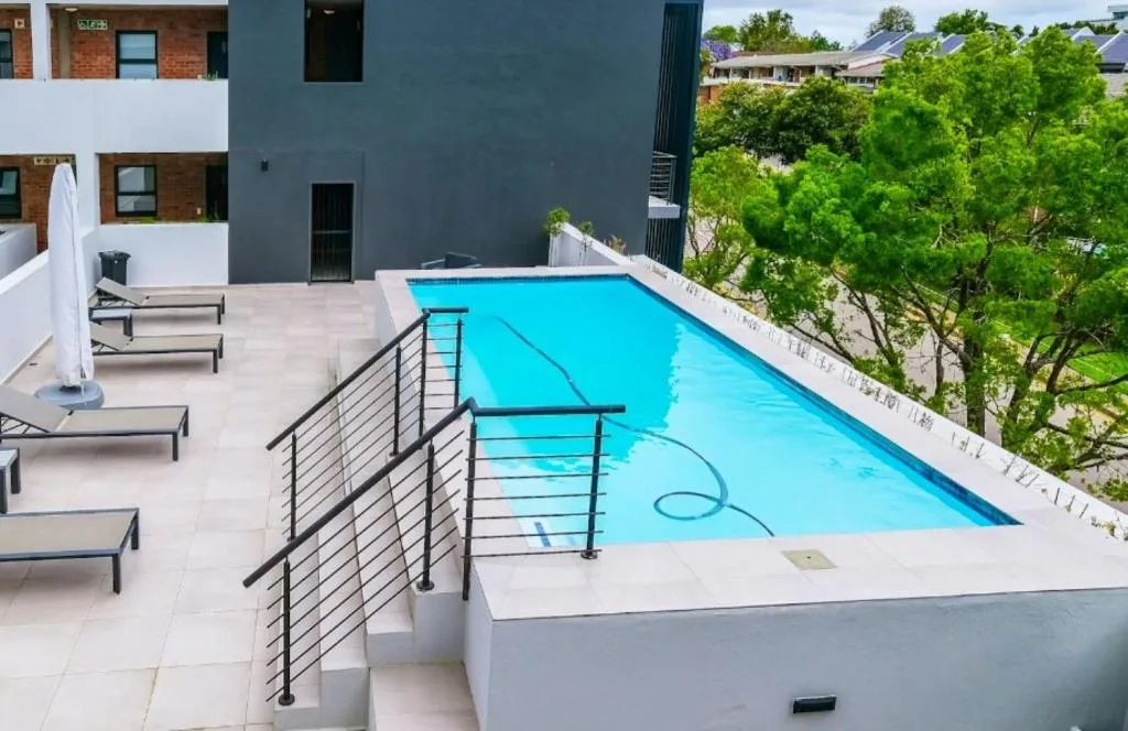 Bright turquoise swimming pool on modern rooftop deck with loungers