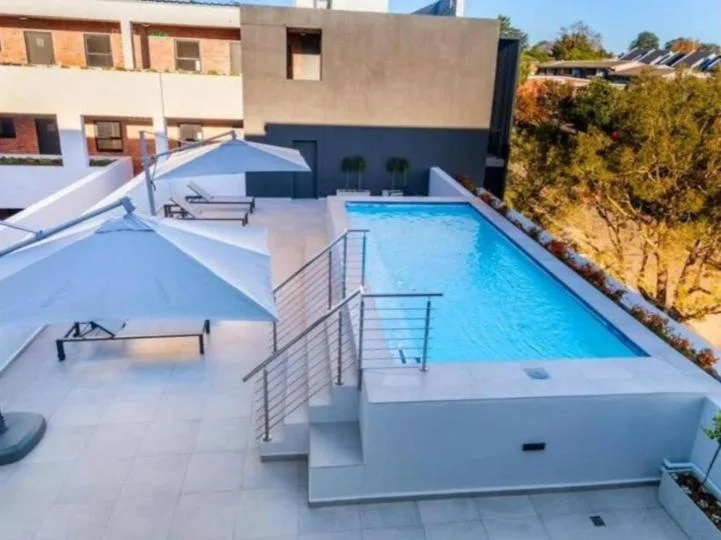 Rectangular swimming pool with sun loungers and umbrellas on surrounding deck