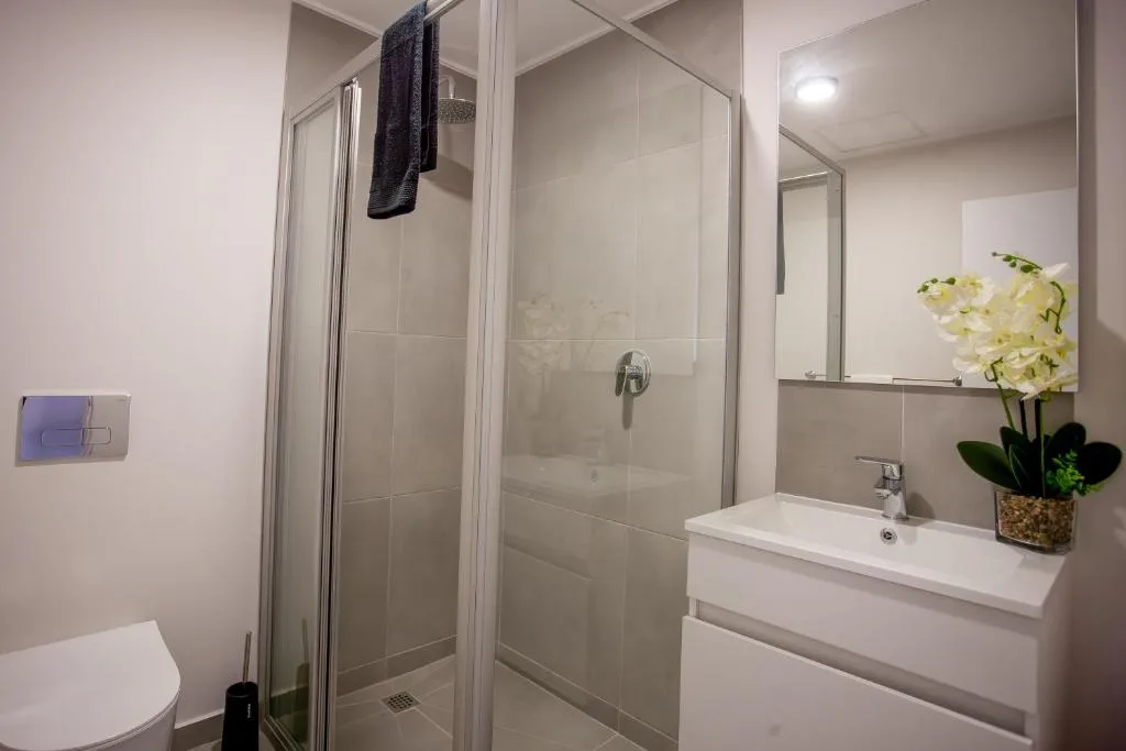 Modern bathroom with glass shower enclosure, white vanity, and fresh flowers