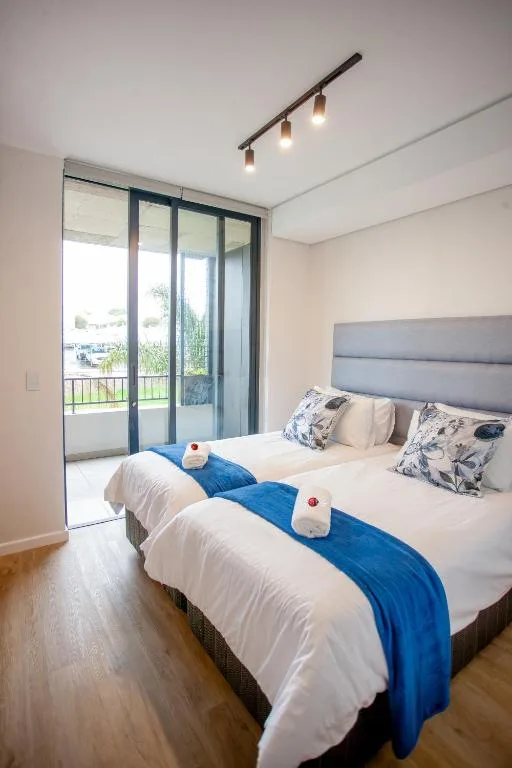 Modern bedroom with double bed, blue accent, sliding glass doors to balcony