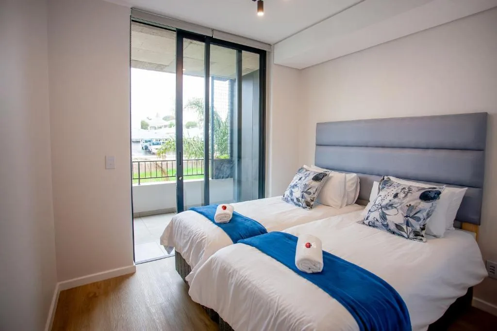 Twin bed bedroom with sliding glass doors opening to deck and garden views