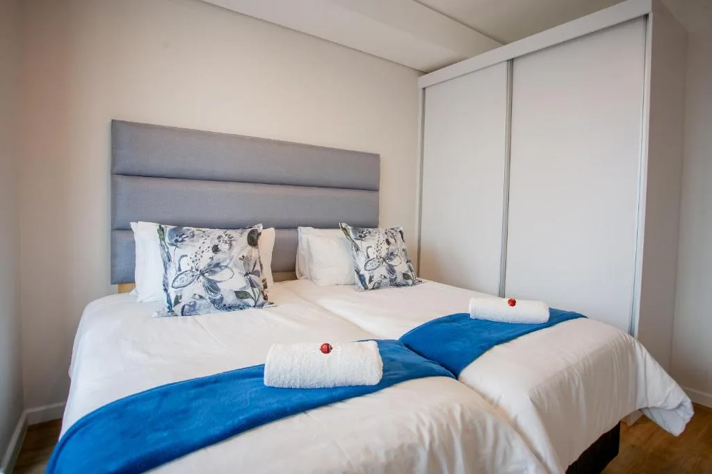Spacious bedroom with twin beds, gray headboard, and modern furnishings