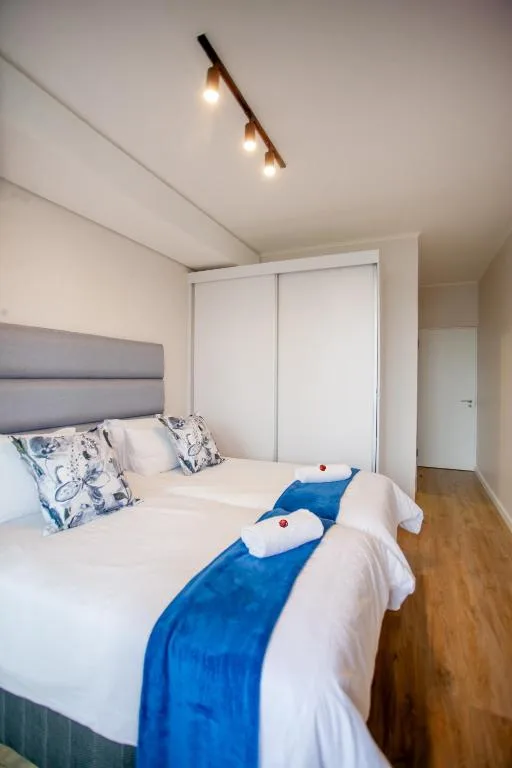 Modern bedroom with twin beds, grey headboard, and sliding wardrobe doors