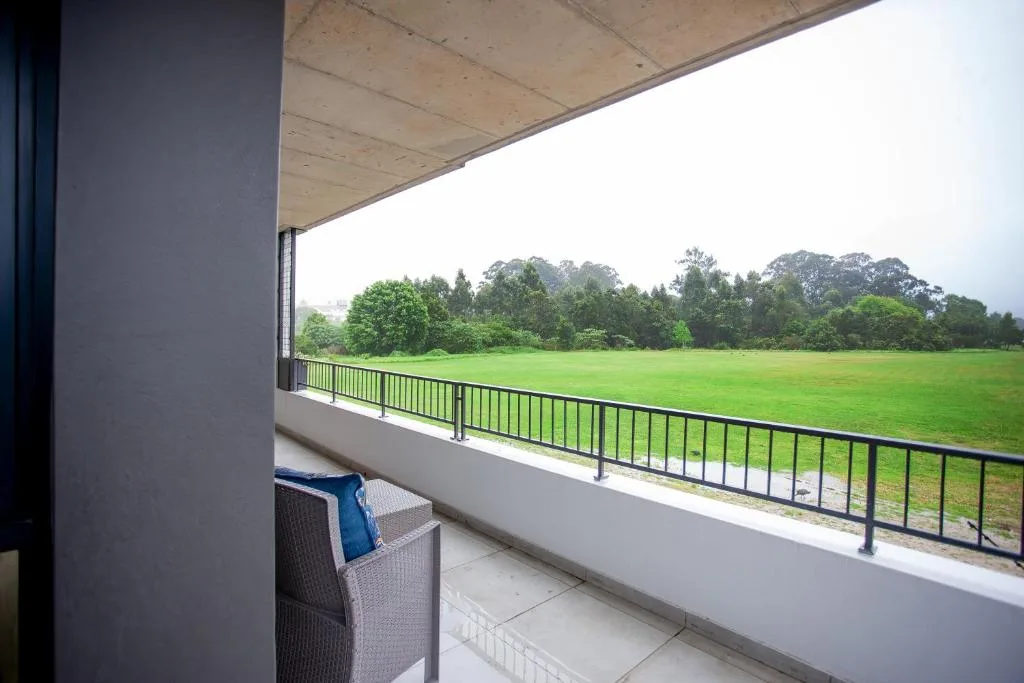 Spacious balcony with railing overlooking expansive green meadow and trees