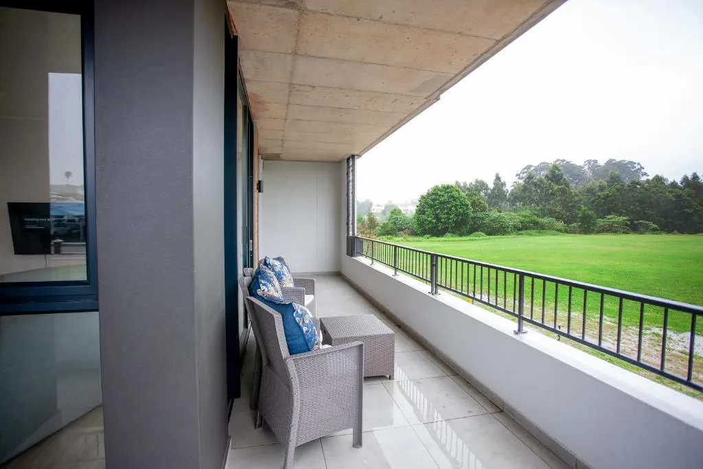Modern balcony with rattan chair overlooking lush green meadow and forest
